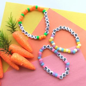 close up of easter bead friendship bracelet craft for tween on colourful backdrop with toy carrots