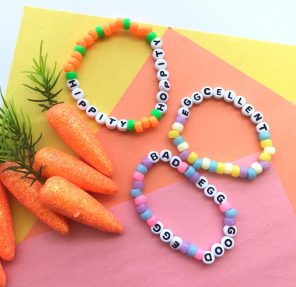 close up of easter bead friendship bracelet craft for tween on colourful backdrop with toy carrots
