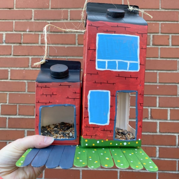 homemade bird feeder milk carton with brick house in background