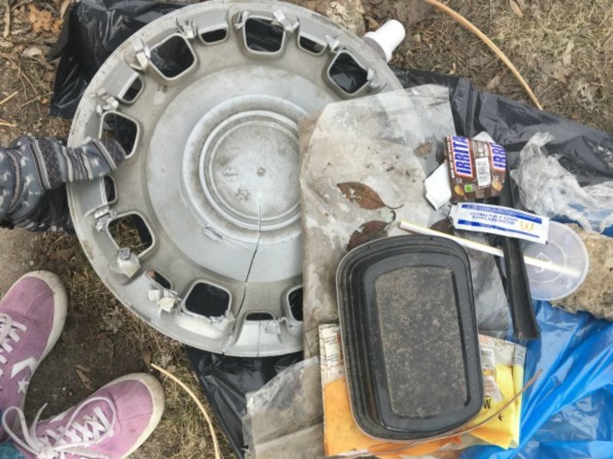pile of garbage on lawn with kid's shoes, hubcap, and more