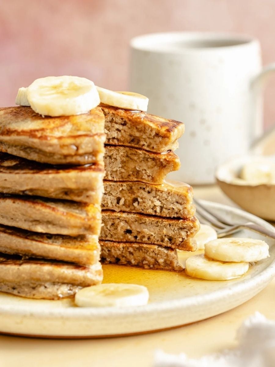 plate of banana and oatmeal pancakes topped with sliced banana and maple syrup