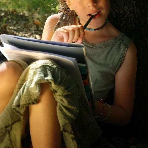 tween writing a story under a tree