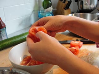 peeling tomatoes into bowl