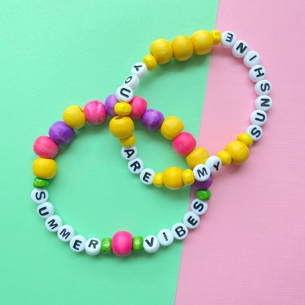 summer friendship bracelets with letter beads on colourful background