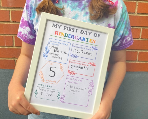 child with first day of kindergarten sign in her hands