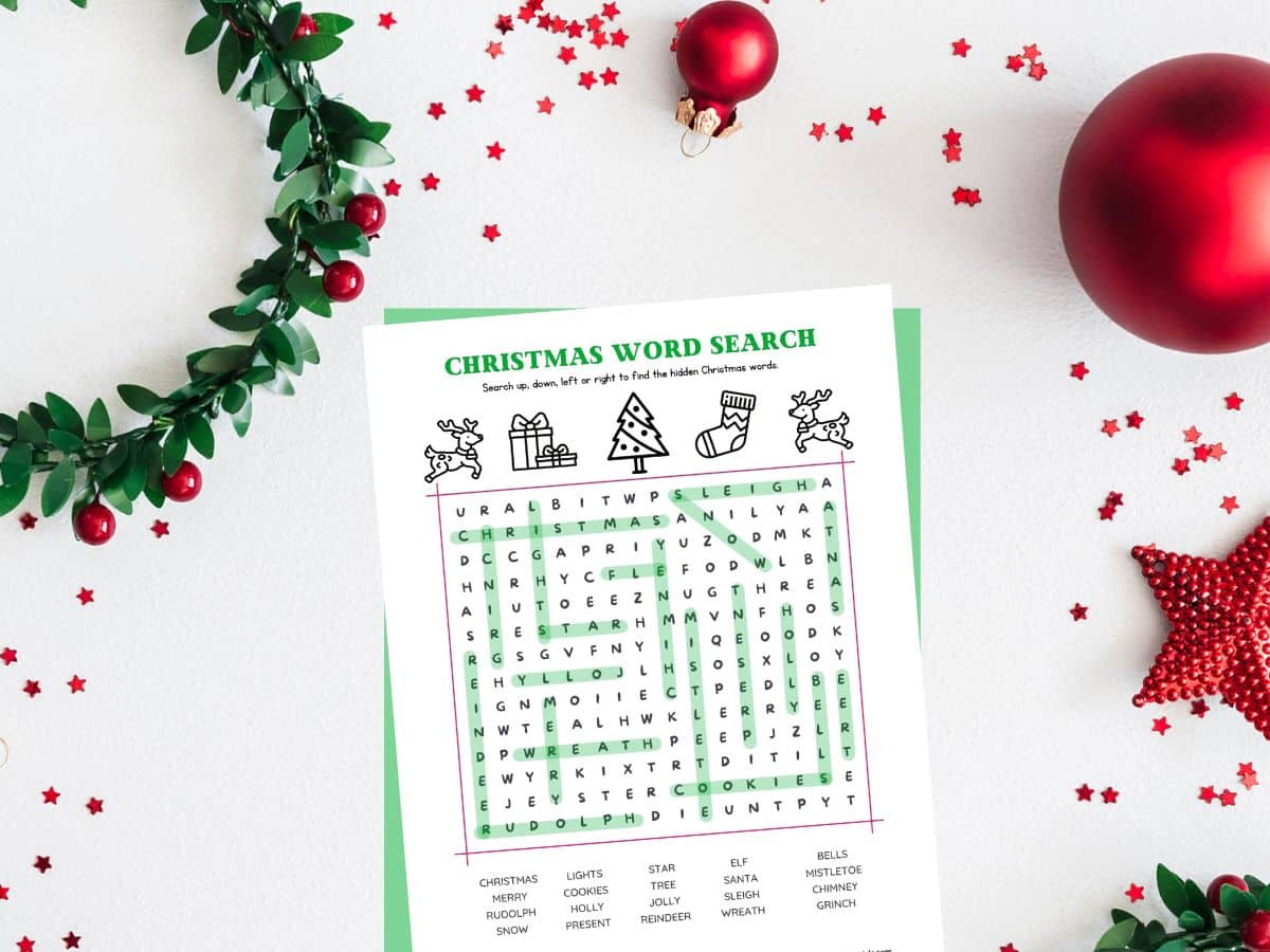 christmas word search answers on table with red ornaments and wreath