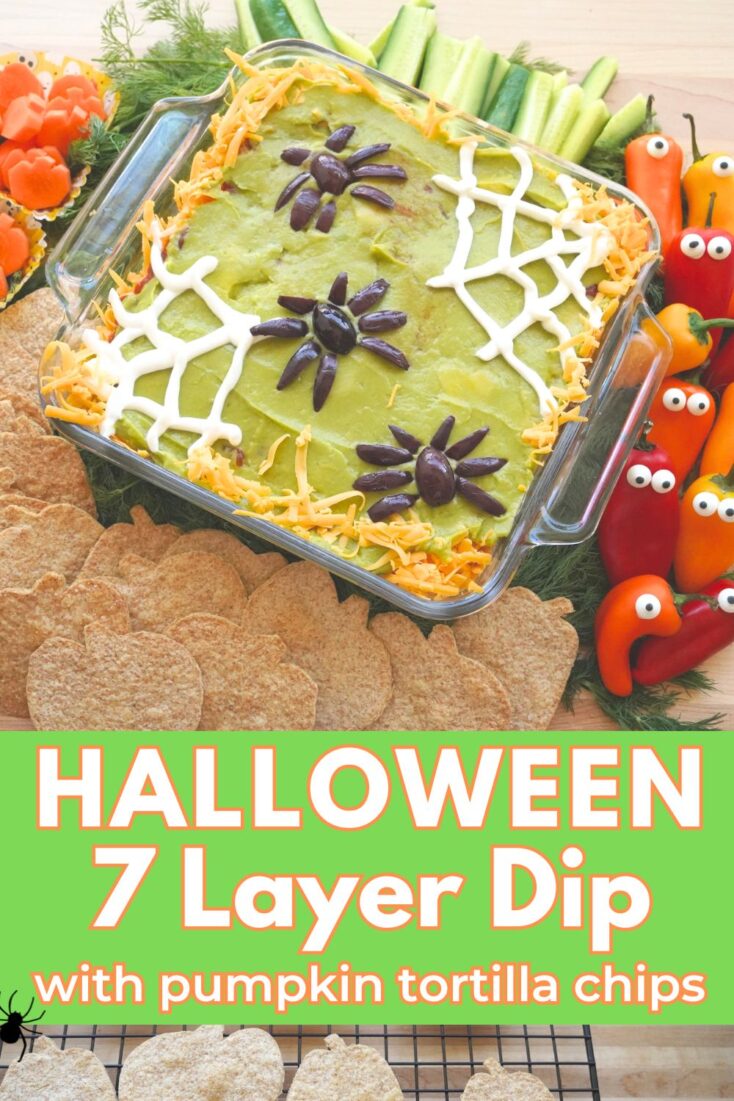 Halloween 7 layer dip with olive spiders and sour cream spider web surrounded by carrot pumpkins and pumpkin tortilla chips. Title "Halloween 7 Layer Dip and Pumpkin Tortilla Chips"