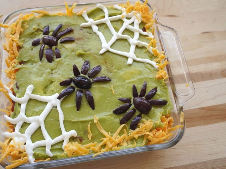 seven layer dip with sour cream spider webs and olive spider on top
