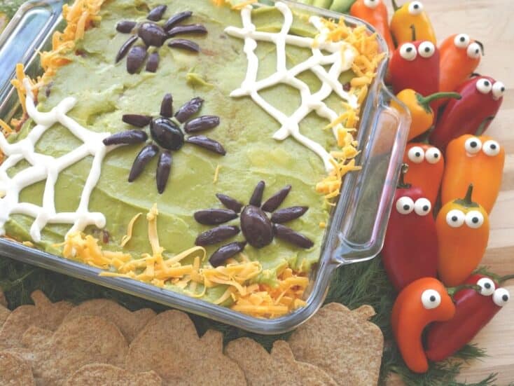 Halloween 7 layer dip with sour cream spider webs and pumpkin tortilla chips