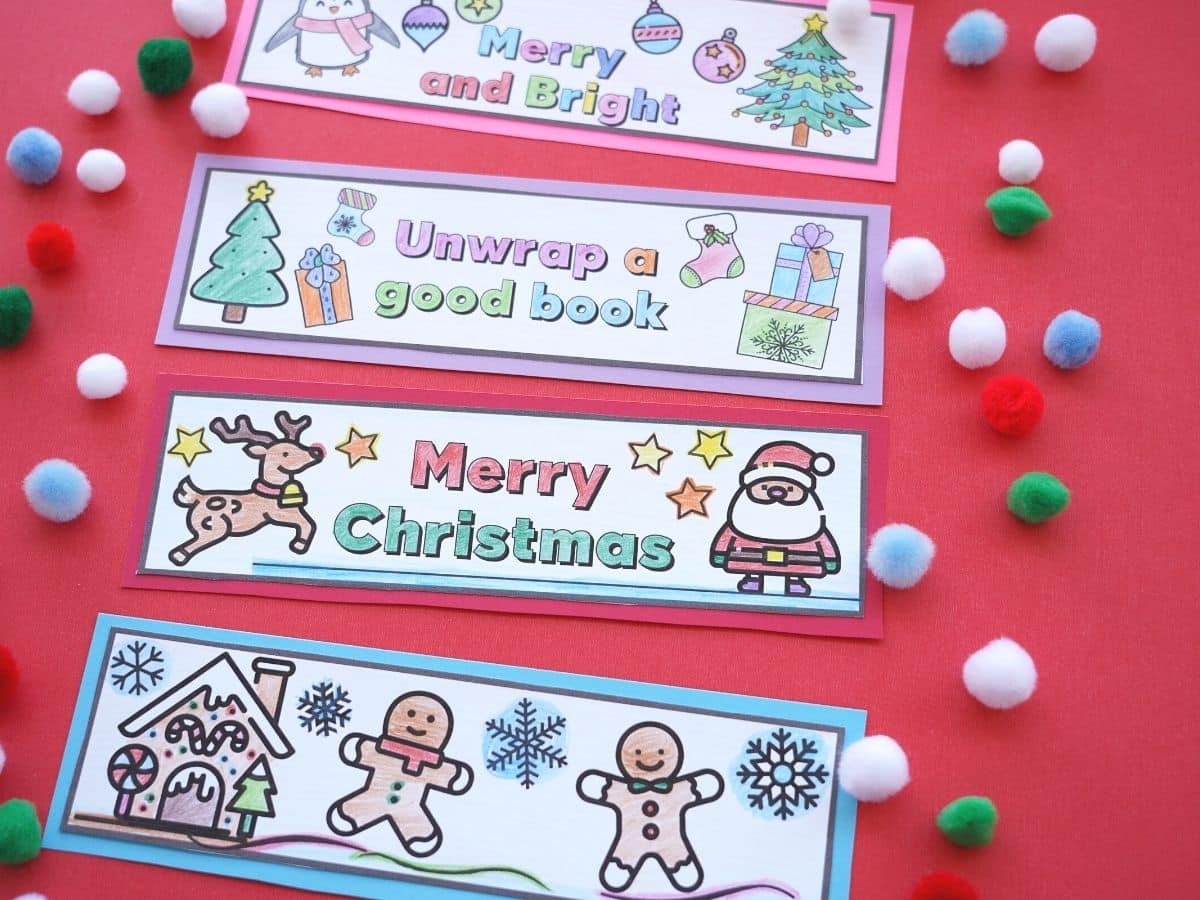 christmas bookmarks printed out and coloured with a pile of pom poms