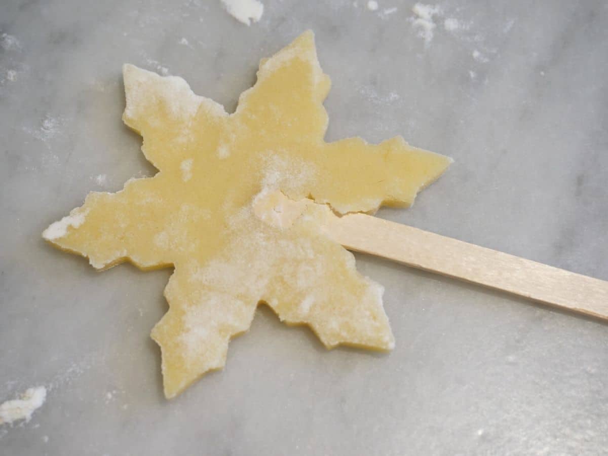 christmas cookie pop dough cut into snowflake and on popsicle stick