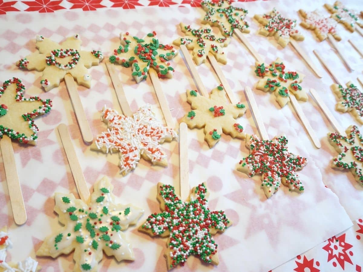snowflake christmas cookie pops decorated on parchment paper