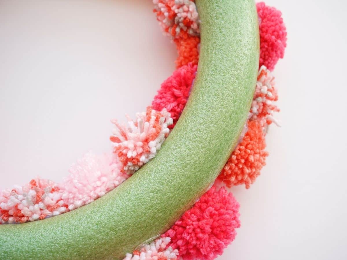 back side of valentine pom poms glued to green wreath form