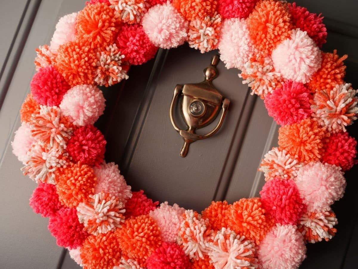 valentines pom pom wreath hanging on the front door