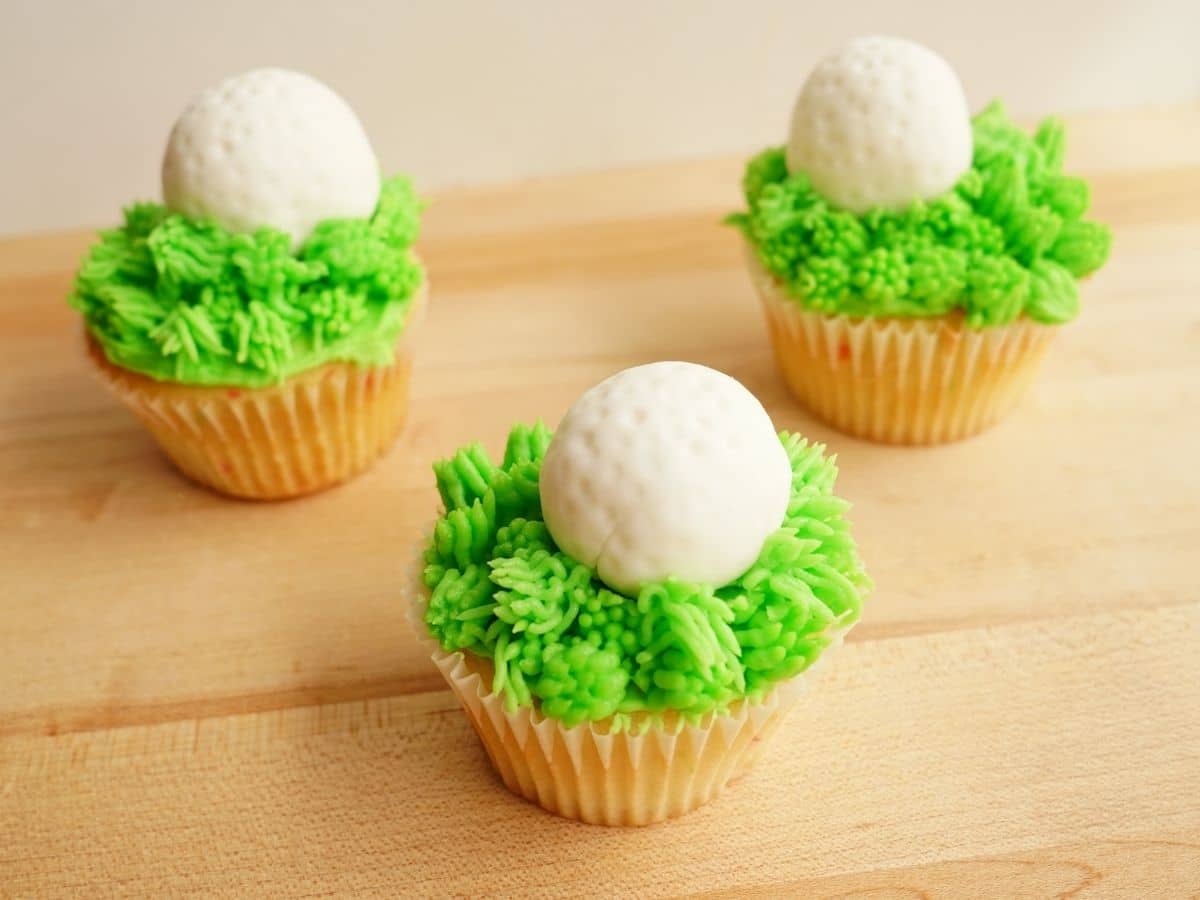 3 golf cupcakes with chocolate stuffed fondant golf balls and long rough grass buttercream