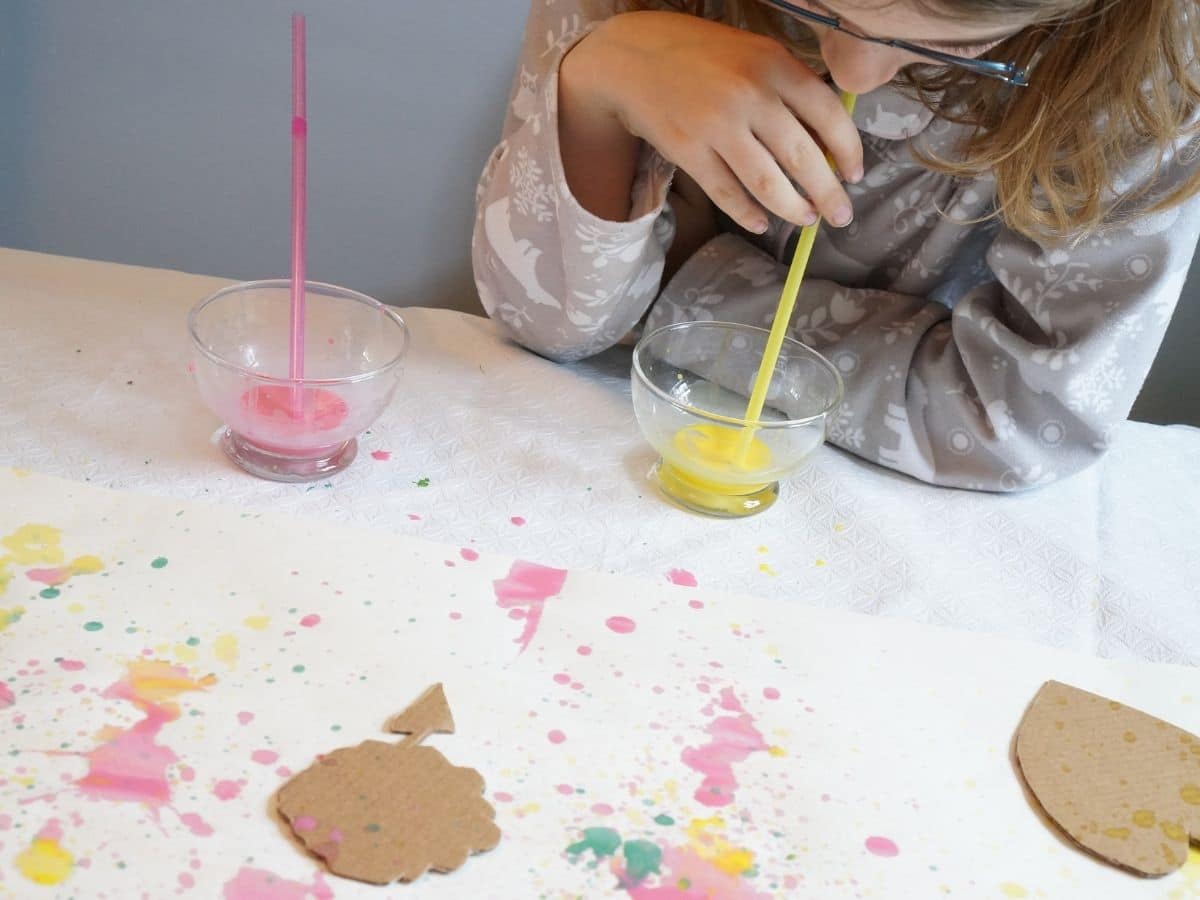 blow art kid with paint and straw and paper painted