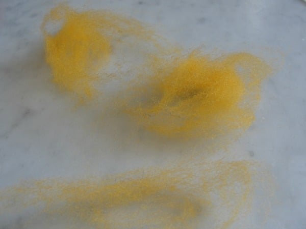 fluffy pile of yellow wool roving on table
