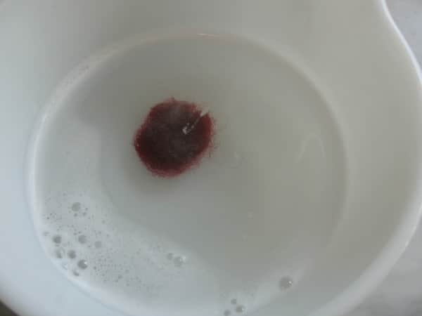 ball of wool roving in a bowl with hot water and dish soap