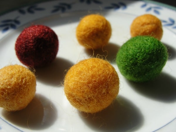 6 wool felt balls on plate sitting drying in the sun