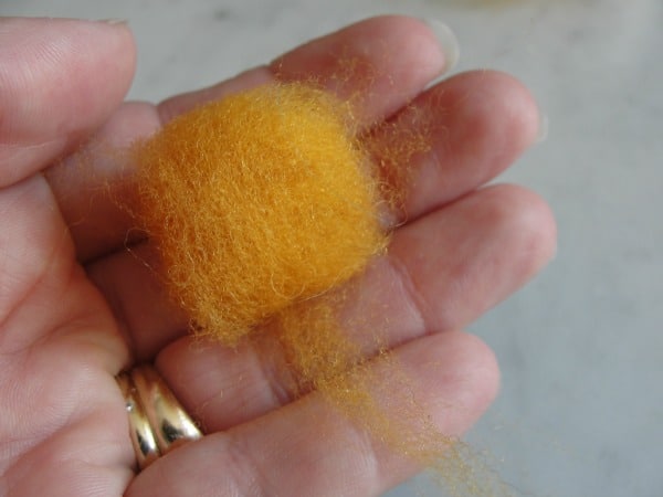 yellow wool roving spun into a ball in a hand