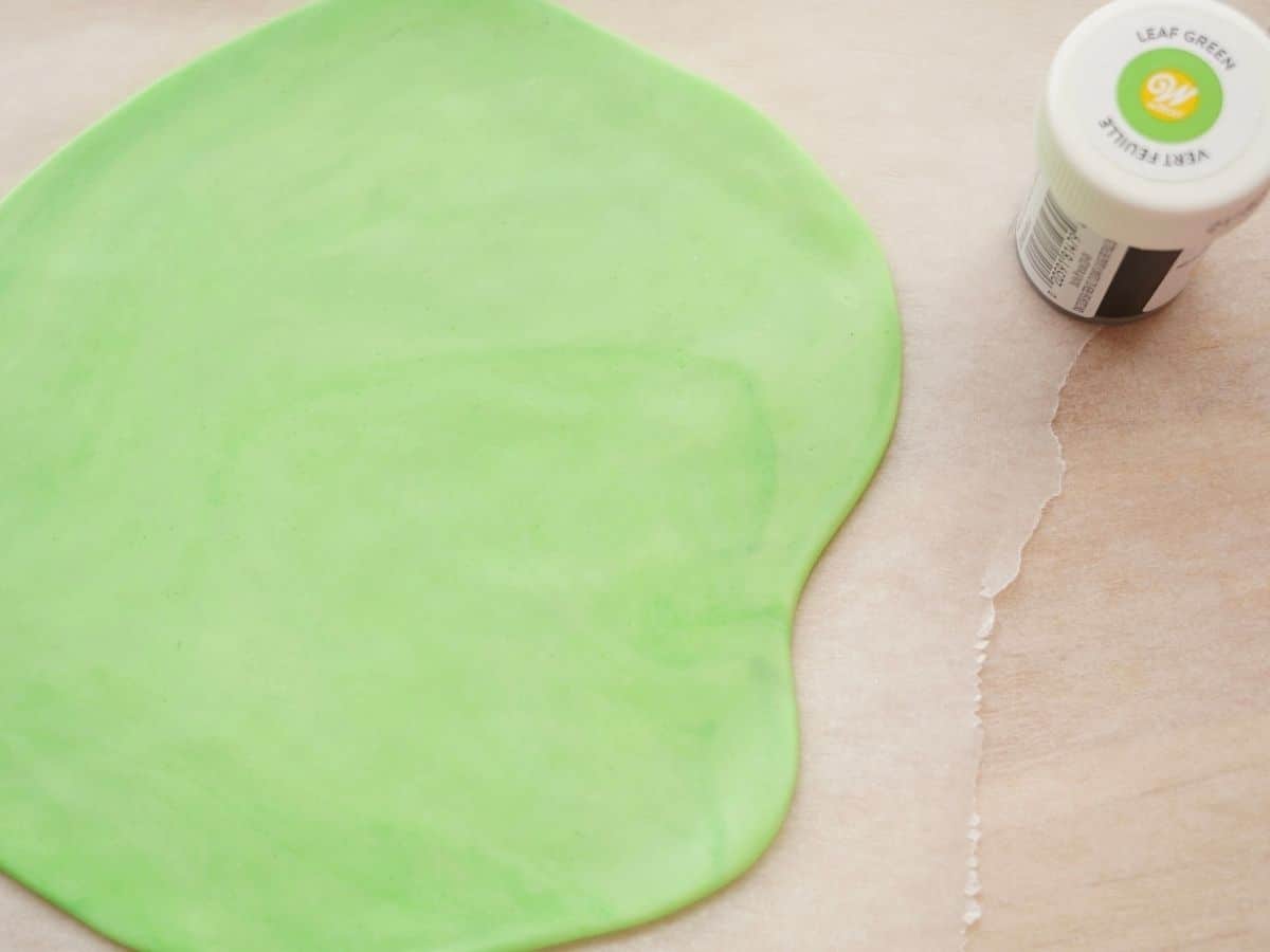 green fondant rolled out with a bottle of leaf green food coloring