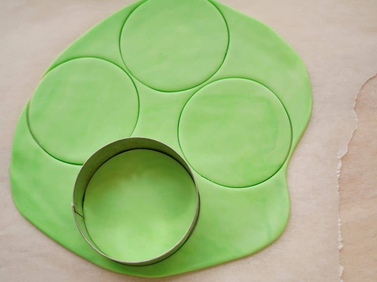 green fondant rolled out with circle cookie cutter on it