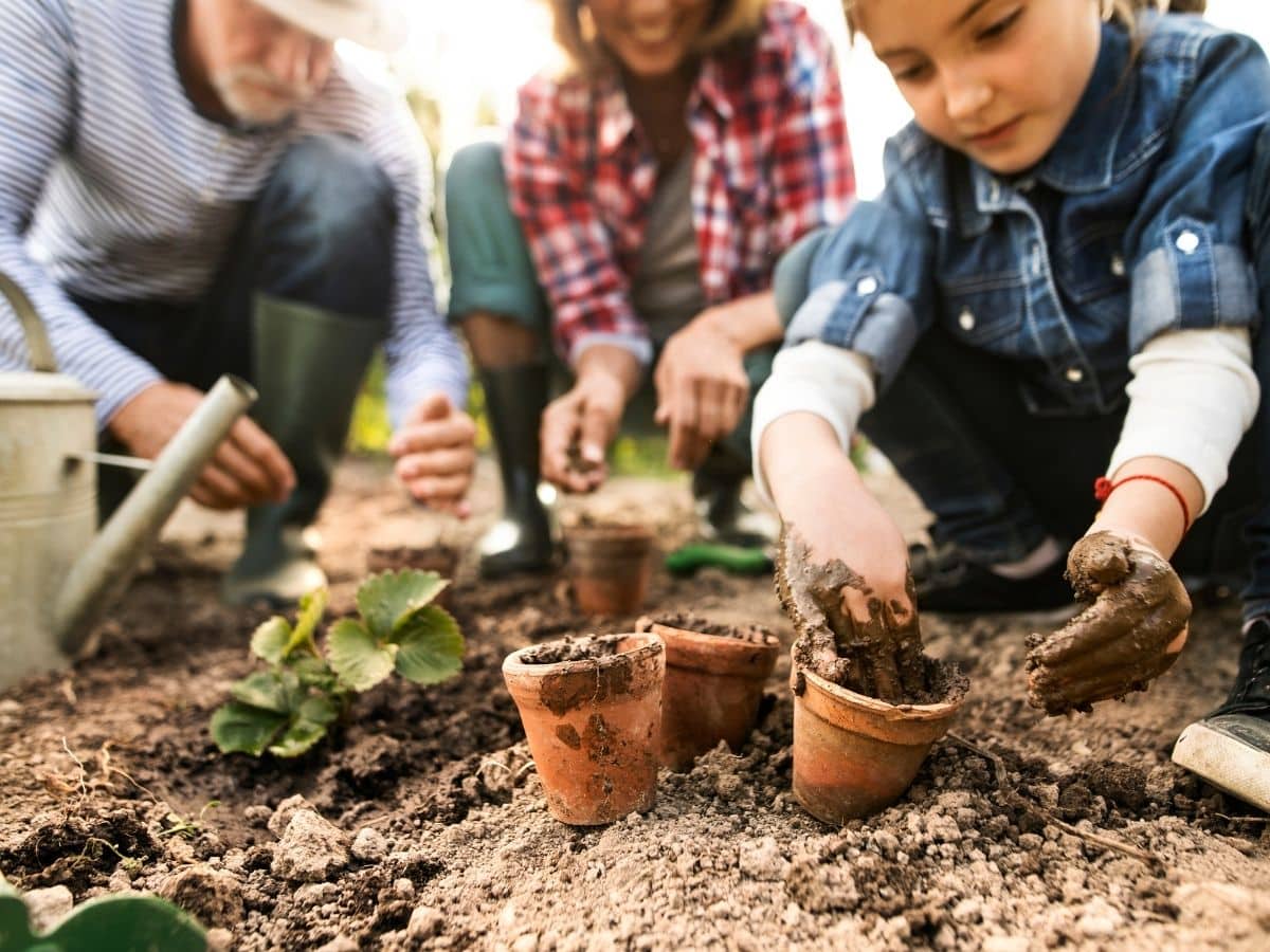 mom dad and daughter planting in garden green living ideas for families