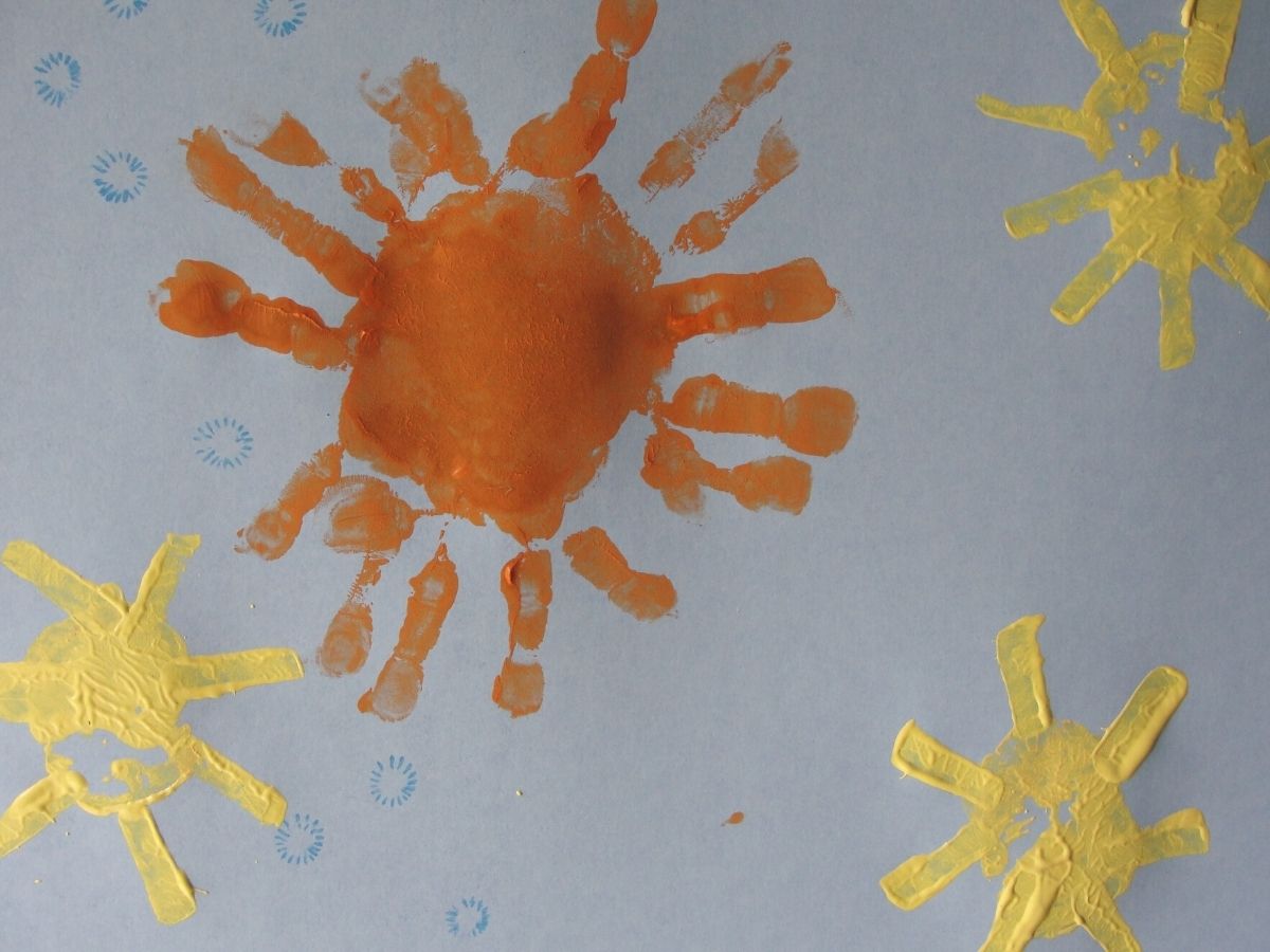 handprint sun stamping art piece with orange and yellow handprint suns