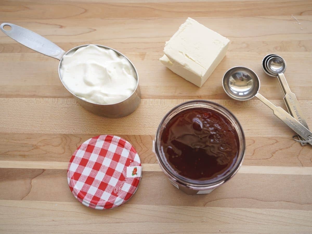 greek yogurt block of cream cheese and strawberry jam jar on wooden table