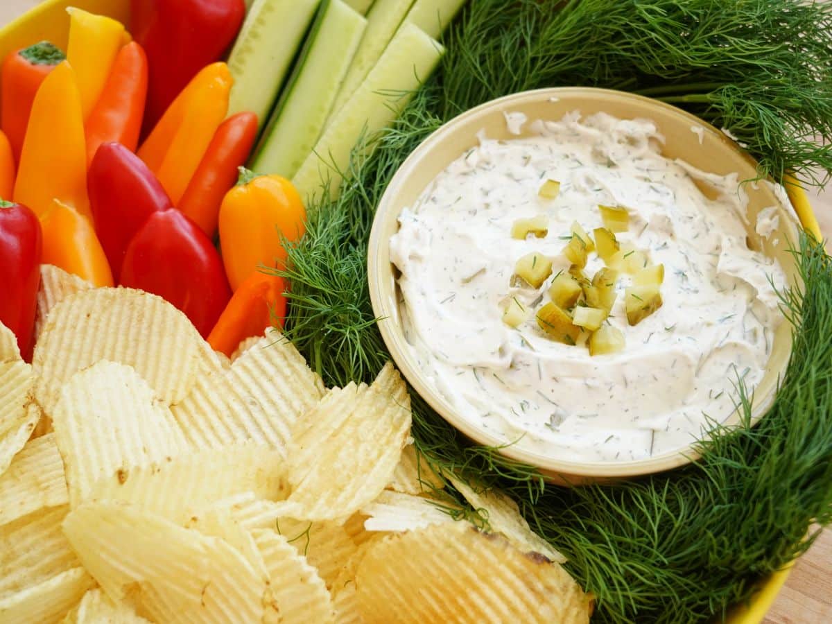 bowl of dill dip with chips, sweet peppers and cucumbers