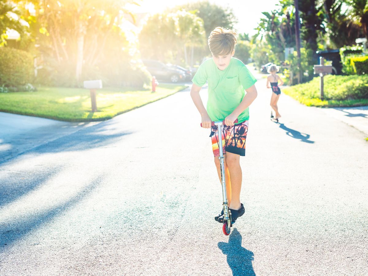 2 older kids on scooters on neighbourhood street