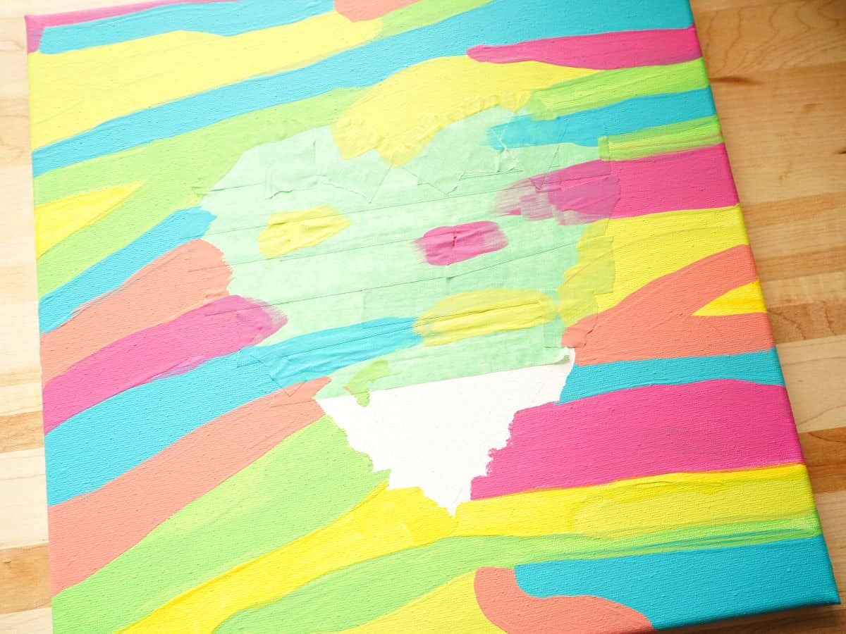 painters tape heart on canvas with some of the tape peeled off