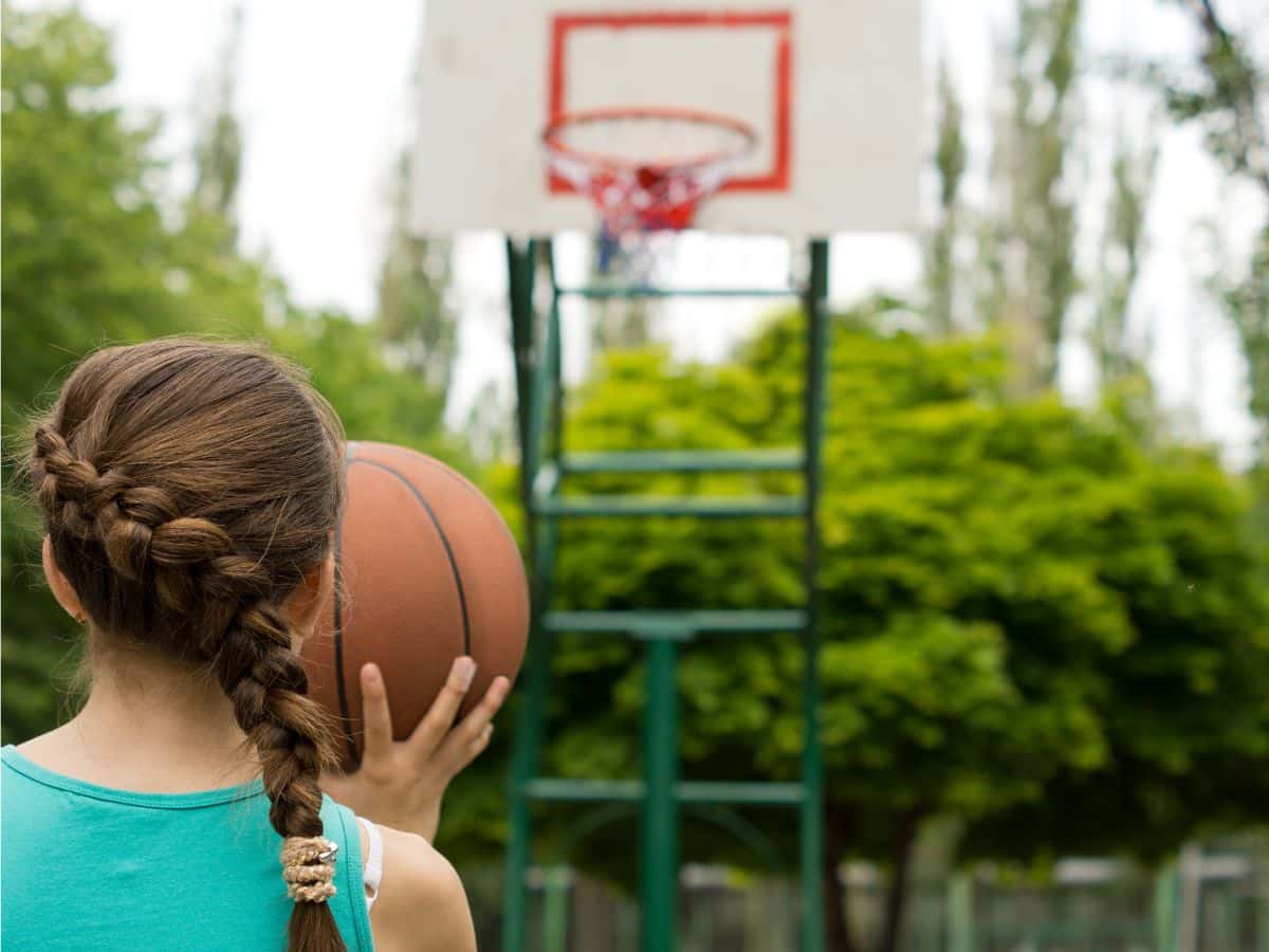 tween girl setting up a basketball shot at the hoop