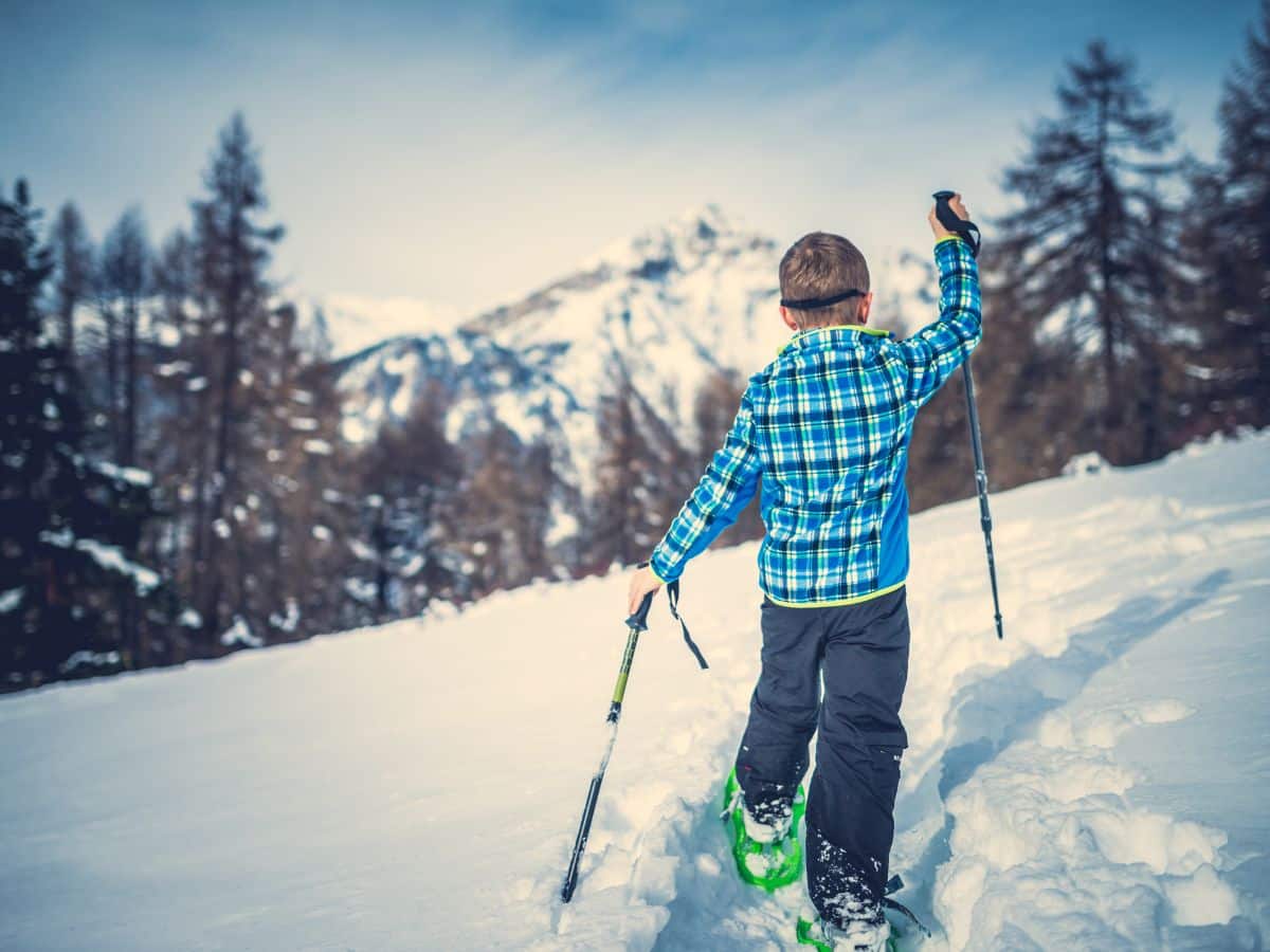 tween kid on snowshoes walking on a path
