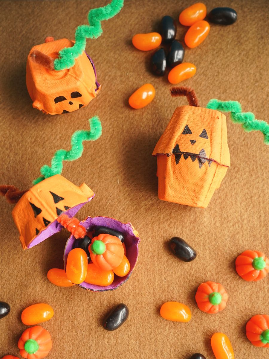 3 egg carton jack olantern treat boxes with candies inside and candies all around