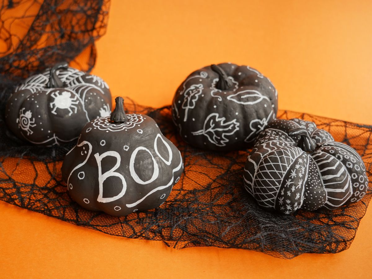4 chalk marker pumpkins on orange background with black lace