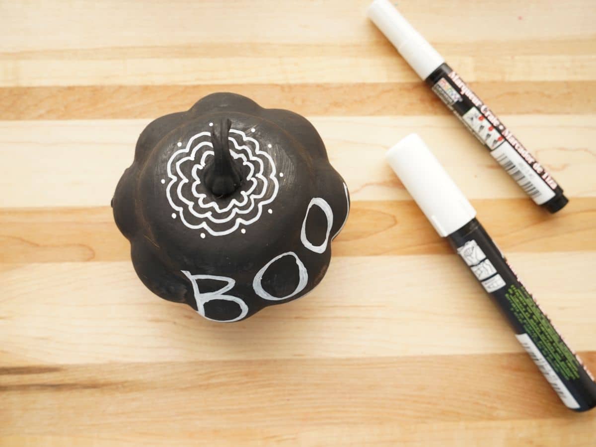 top view of chalk markers on pumpkin with doodle design and chalk marker