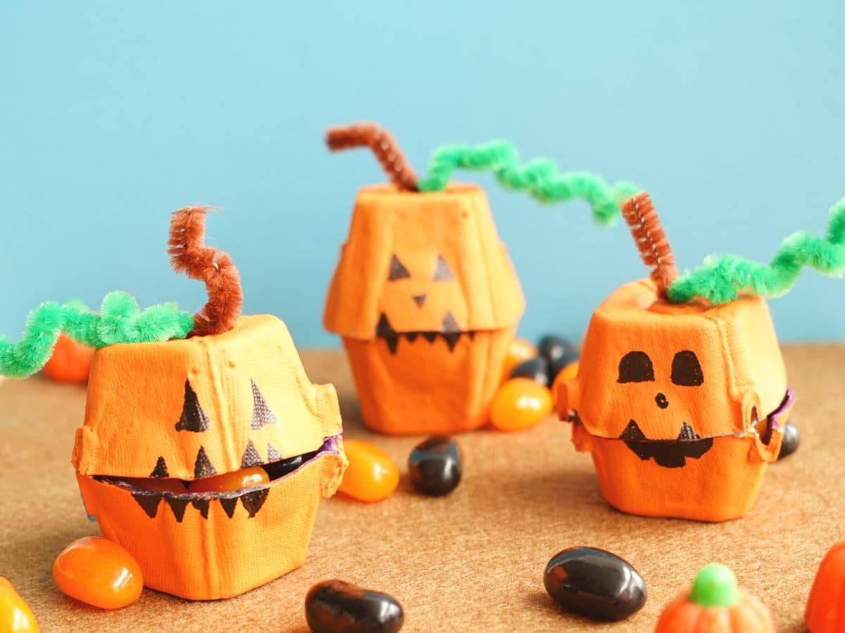 3 egg carton jack o'lanterns candy boxes with candies inside and Halloween candies all around