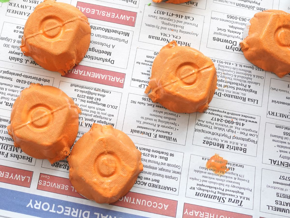 egg carton cells painted orange on newspaper