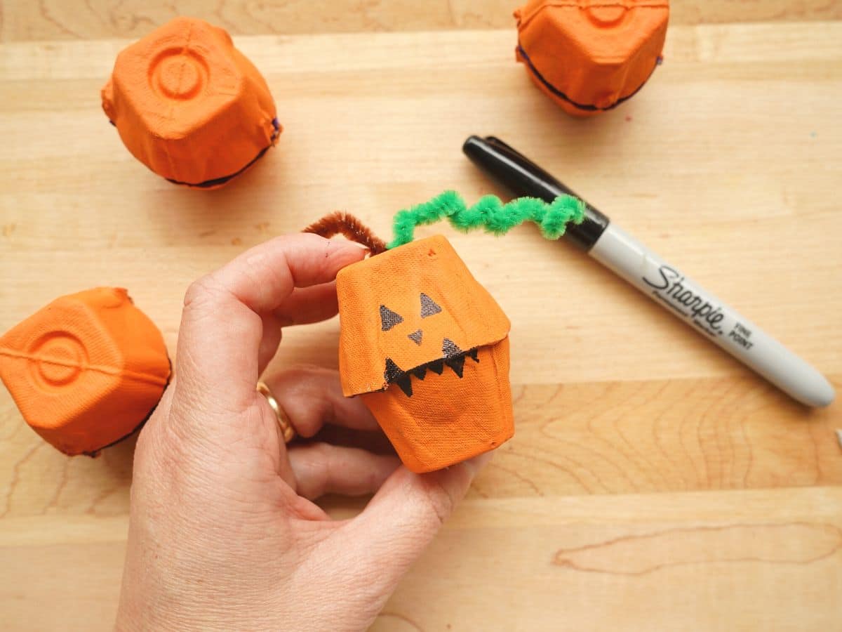 jack o'lantern faces drawn on egg carton pumpkins with black sharpie marker