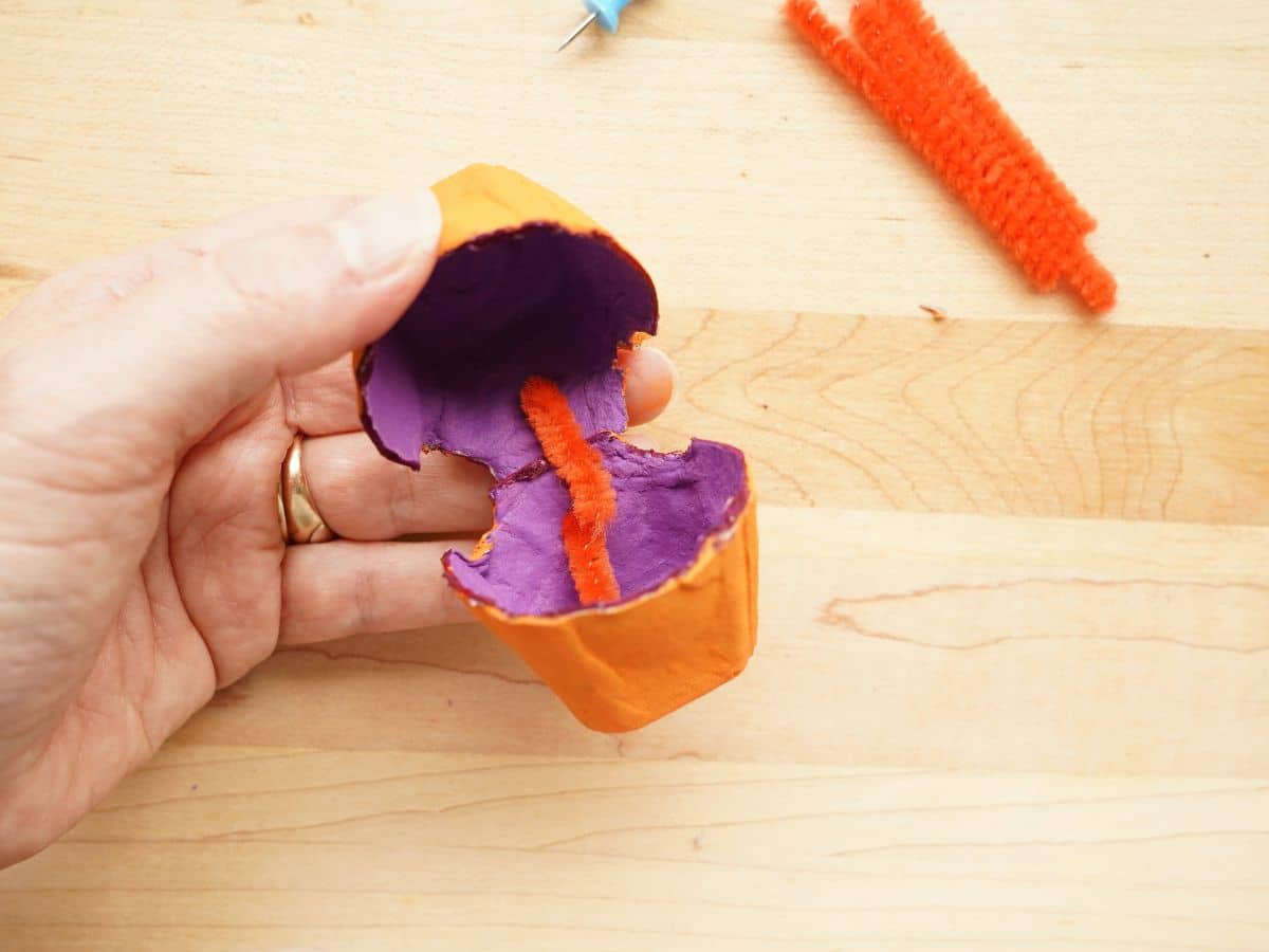 hand holding egg carton pumpkin candy box with the pipe cleaner hinge