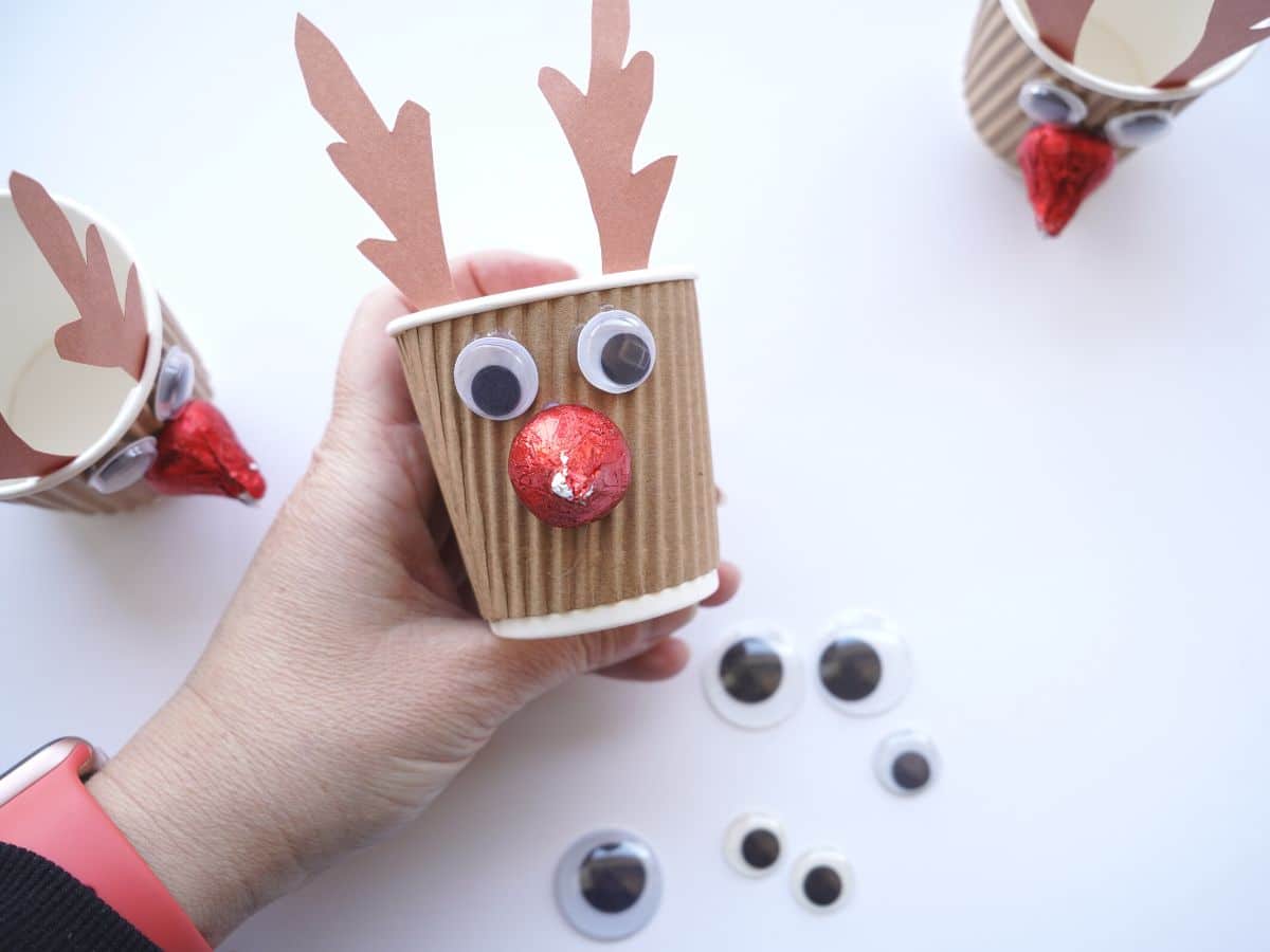 googly eyes glued on rudolph paper cup craft being held in hand