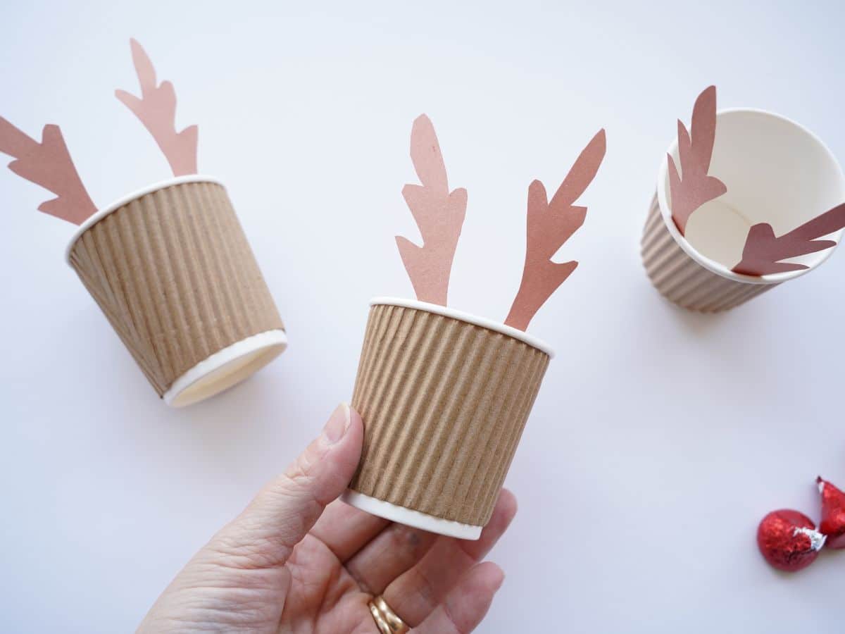 brown cup with reindeer antlers taped inside, held in hand