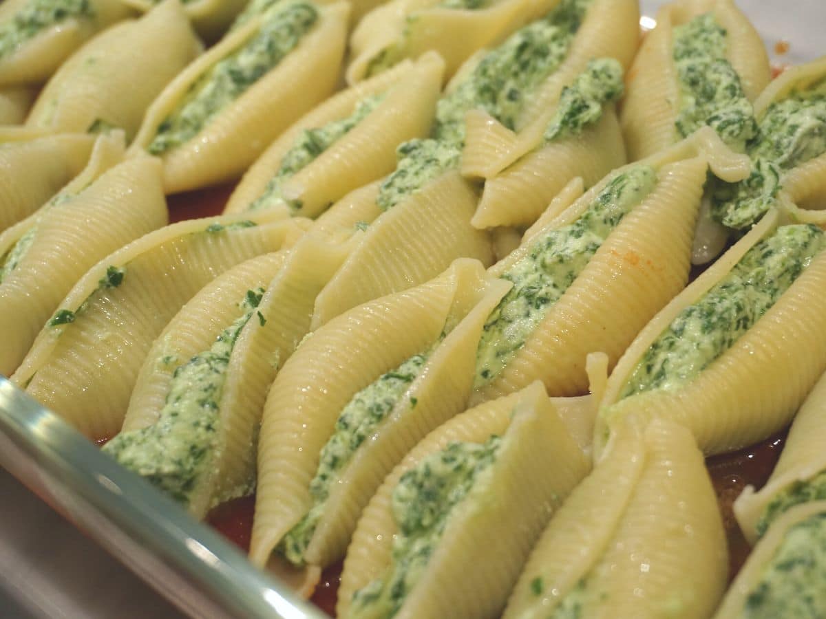 lasagna pan lined with stuffed pasta shells with ricotta and spinach filling ready to bake