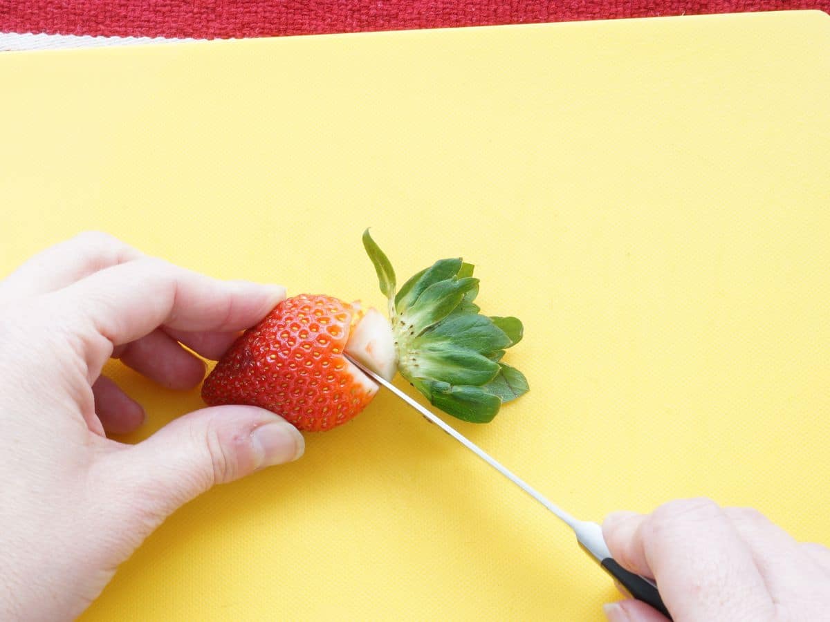strawberry being cut into a heart with paring knife