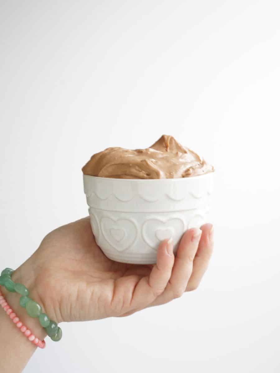 white bowl filled with chocolate dip for fruit in woman's hand