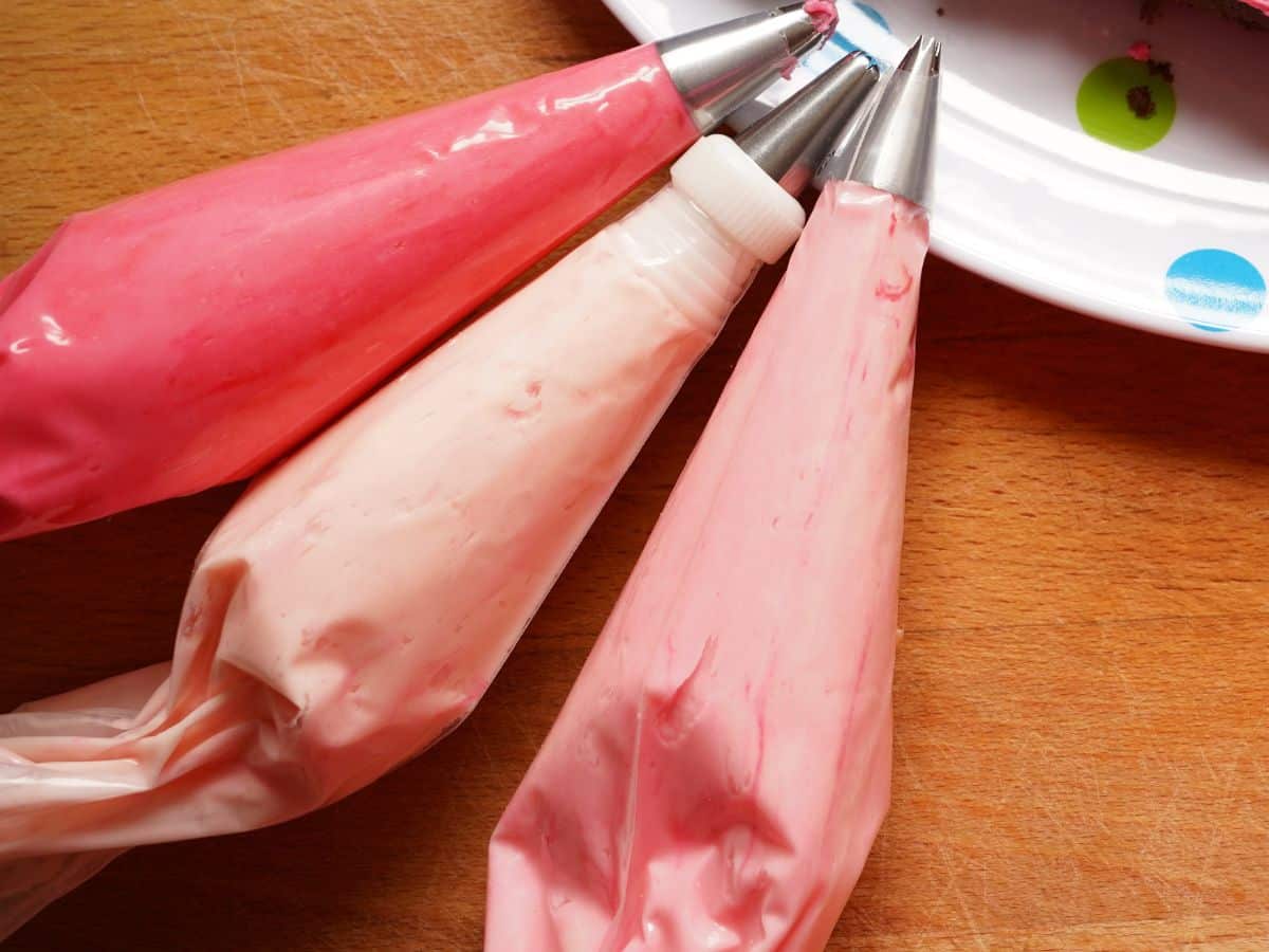3 piping bags filled with 3 shades of pink frosting