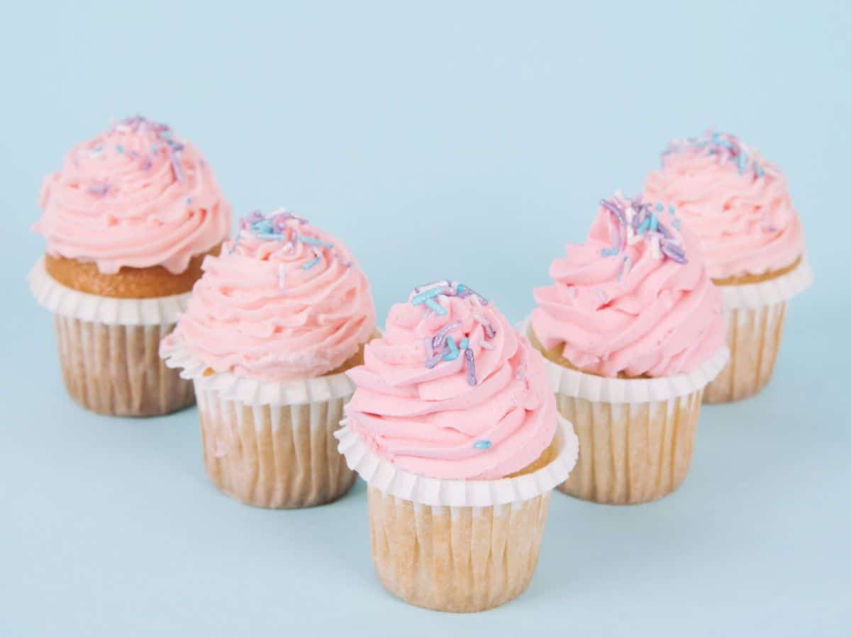 5 pink cupcakes with blue background