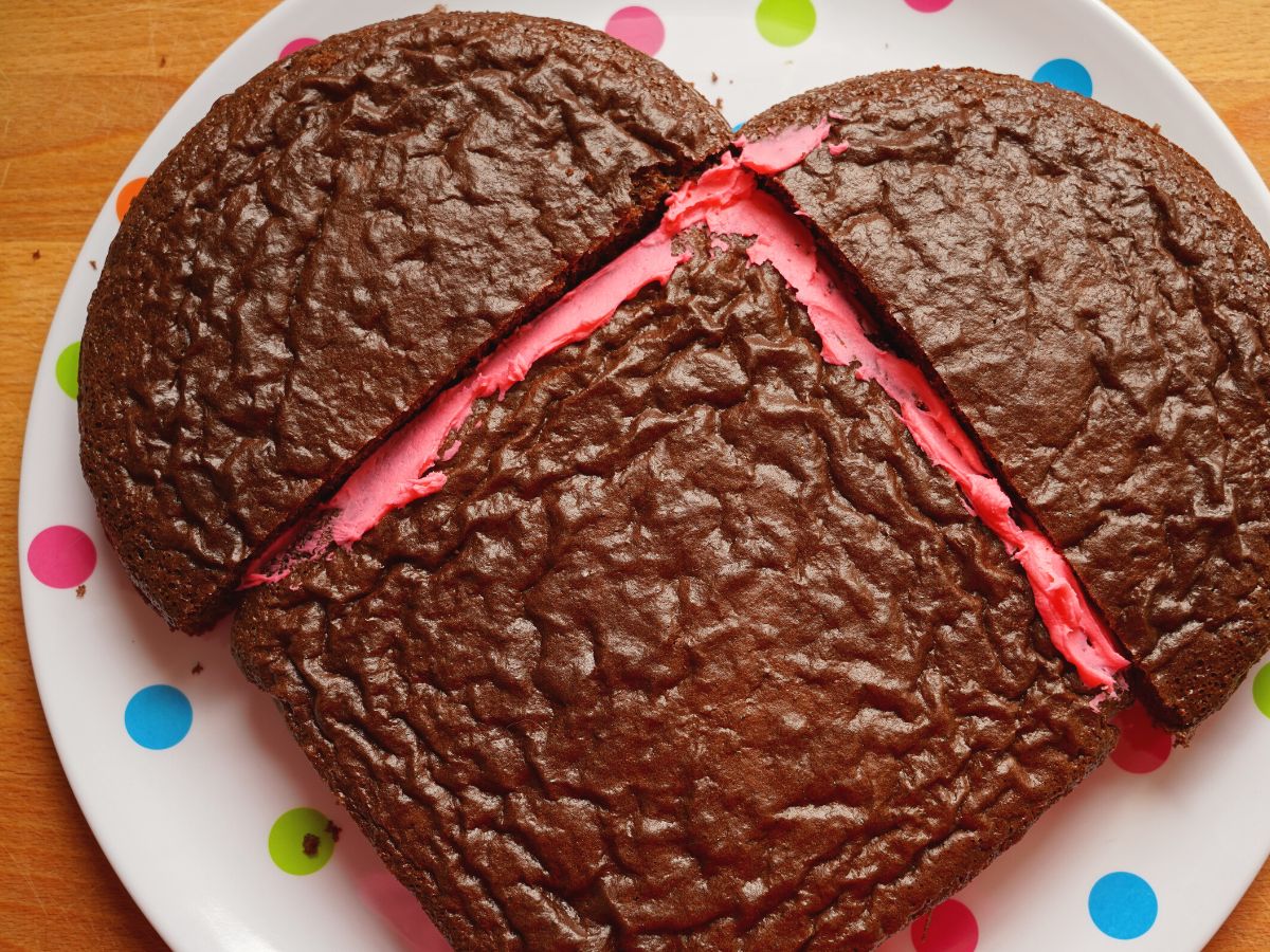pink icing between square chocolate cake and round chocolate cake cut into large heart cake