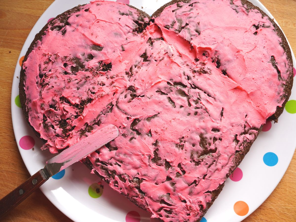 pink icing crumb coat on chocolate heart shaped valentine's day cake